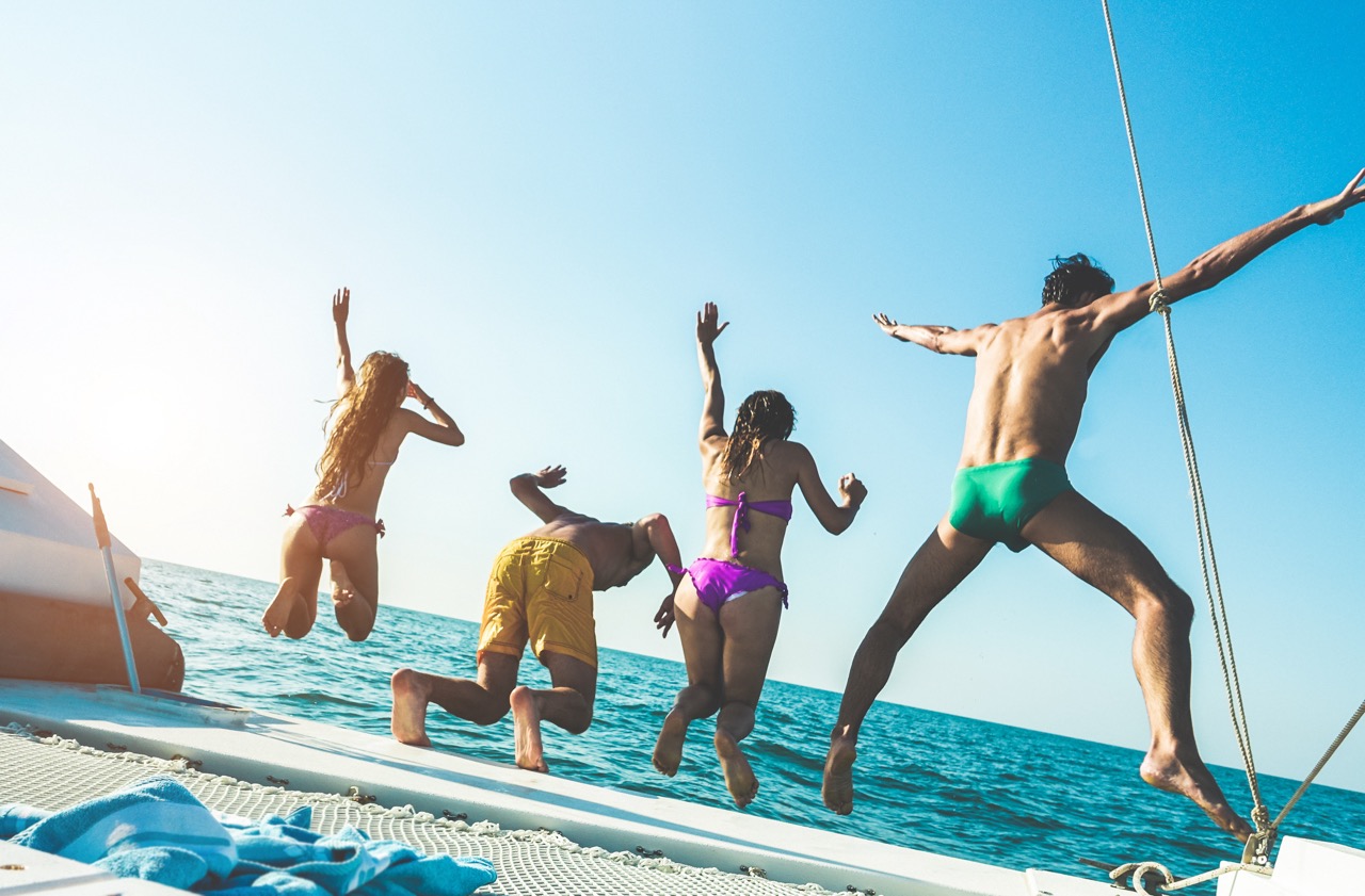 Crazy friends jumping off the boat into the ocean - Young happy people having fun diving into the sea - Travel, summer vacation, tropical and friendship concept - Focus on right guy head